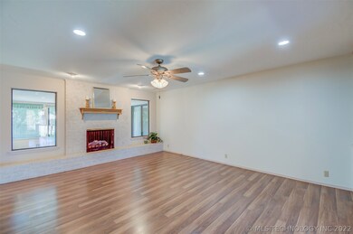 Large living area with gas log fireplace, brick hearth, lots of lighting and windows into the sunroom.