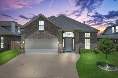 View of front facade featuring concrete driveway, brick siding, and roof with shingles