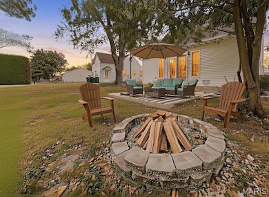 Digitally Staged View of grassy yard featuring a patio area and an outdoor fire pit