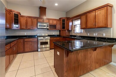 Kitchen featuring kitchen peninsula, stainless steel appliances, decorative backsplash, and light tile patterned floors