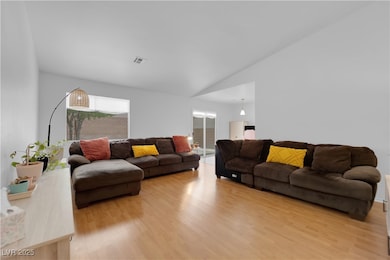 Living room with light wood-type flooring and vaul