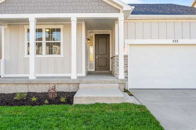 Doorway to property featuring board and batten siding, an attached garage, a shingled roof, and concrete driveway