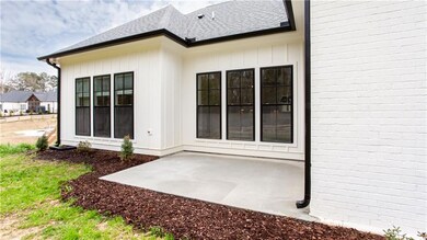Rear view of property with roof with shingles, a patio area, and board and batten siding