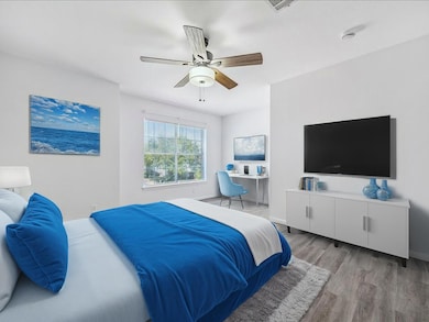 Bedroom with light wood-style flooring, a desk, and a ceiling fan