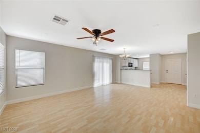 Unfurnished living room with light wood-style floors, a chandelier, and a ceiling fan