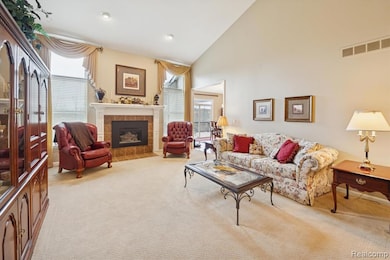 Spacious living room with vaulted ceilings, neutral carpeting, and a gas fireplace framed by two tall windows.