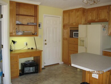 Desk and book or display shelves in kitchen. Entrance to garage