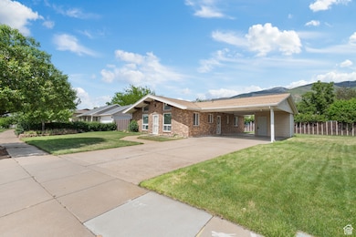 Single story home with concrete driveway, a carport, a mountain view, and brick siding