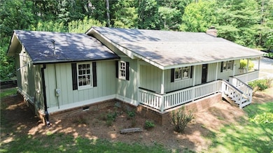 View of front facade featuring covered porch, a chimney, roof with shingles, and crawl space