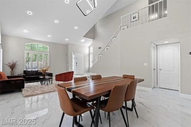 Dining space featuring light marble finish floors, recessed lighting, high vaulted ceiling, and stairs