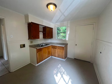 Kitchen featuring a sink, baseboards, and light countertops