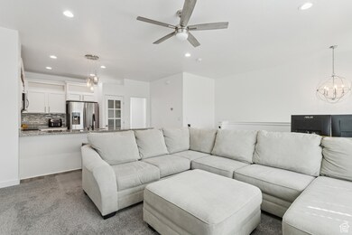 Carpeted living area featuring a chandelier, recessed lighting, and a ceiling fan