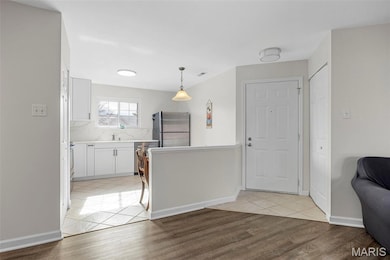 Kitchen featuring light countertops, stainless steel appliances, decorative light fixtures, and light wood finished floors