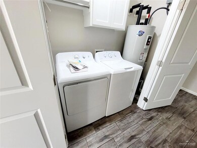 Laundry area featuring washing machine and clothes dryer, cabinets, and water heater
