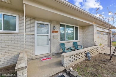 Entrance to property featuring covered porch, brick siding, and an attached garage