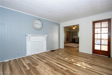 Unfurnished living room featuring crown molding, wood finished floors, and a ceiling fan
