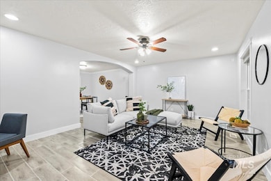 Living room featuring arched walkways, a ceiling fan, recessed lighting, a textured ceiling, and light wood finished floors