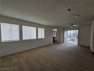 Unfurnished living room with a textured ceiling, carpet, and a ceiling fan