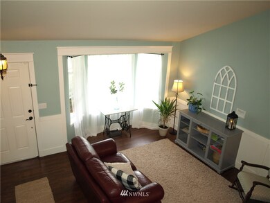 Pretty bay window with custom window casings and moldings brightens the living room, as seen from over the bannister railing.