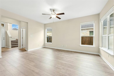Empty room with stairs, a ceiling fan, light wood