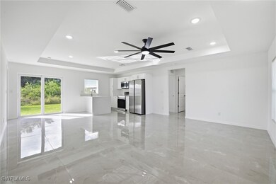 Unfurnished living room with a raised ceiling, light marble finish flooring, a ceiling fan, and recessed lighting