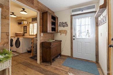 Laundry area with washer and clothes dryer, wood finished floors, and a wall mounted AC