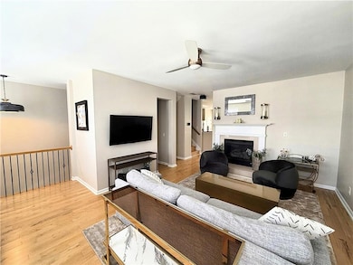 Living area with light wood finished floors, a ceiling fan, a fireplace