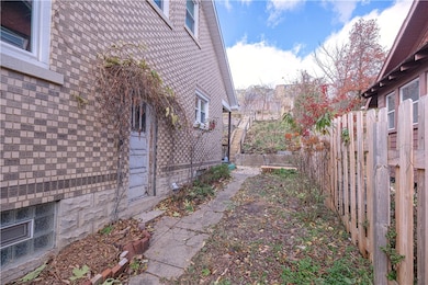 View of side walkway, Basement Door with Keyless Entry, and Wood Slat Fence leading to the Back Porch/Deck from the front of house.
