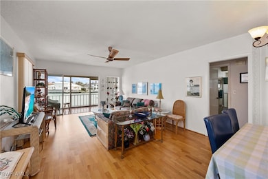Living room with a textured ceiling, light wood-type flooring, and ceiling fan