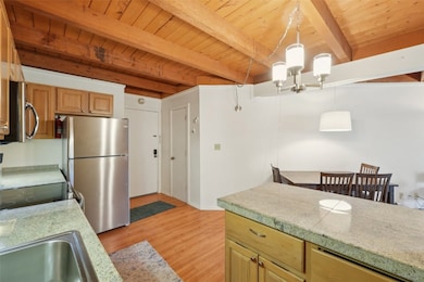 Kitchen featuring stainless steel appliances, a wood ceiling with exposed beams, light wood-type flooring, a chandelier, and hanging light fixtures