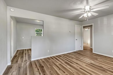 Empty room with wood finished floors, a ceiling fan, and a smoke detector