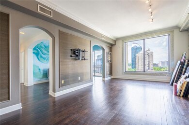 Empty room featuring dark wood-type flooring, crown molding, baseboards, and track lighting