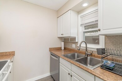 Kitchen with a sink, backsplash, white cabinetry, 