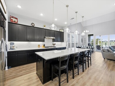 Kitchen featuring dark cabinetry, tasteful backsplash, a breakfast bar area, open floor plan, and hanging light fixtures