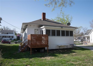 Rear view of house with a yard, roof with shingles, and a chimney