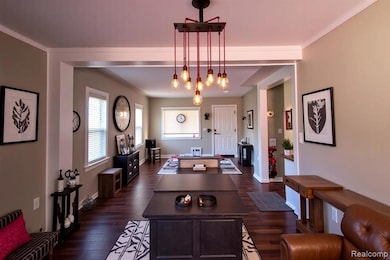 Living room featuring dark wood-style flooring and crown molding