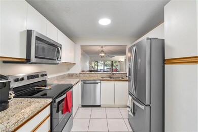 Kitchen featuring appliances with stainless steel finishes, white cabinets, light tile patterned floors, and pendant lighting