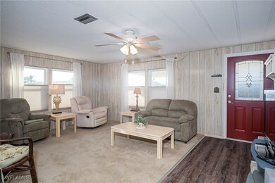 Living room with ceiling fan, wood walls, and wood