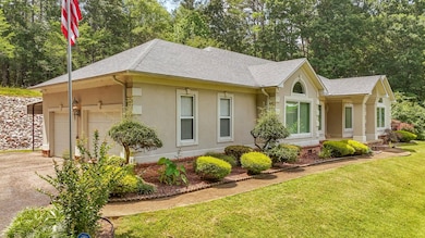 View of front facade featuring roof with shingles, stucco siding, driveway, a front yard, and a garage