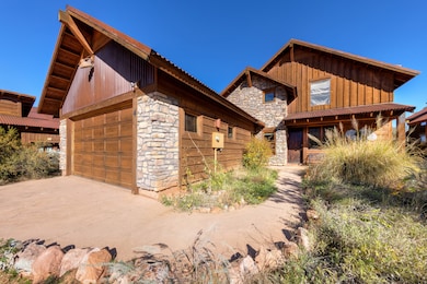 View of front of home with stone siding, a garage, board and batten siding, and an outdoor structure