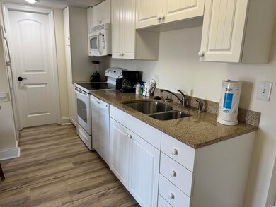 Kitchen with white appliances, wood finished floor