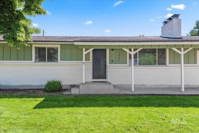 View of front of home with board and batten siding, a front yard, brick siding, and a chimney