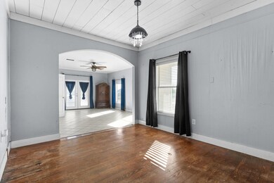 Empty room with arched walkways, plenty of natural light, hardwood / wood-style floors, and ceiling fan
