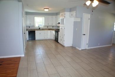 Kitchen featuring white cabinets, wood finish floors, black appliances, and a ceiling fan