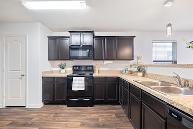 Kitchen featuring black appliances, light counter