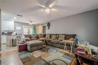 Living area featuring visible vents, a ceiling fan