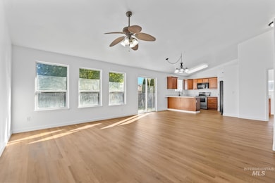 Unfurnished living room with a chandelier, ceiling fan, and light wood-type flooring