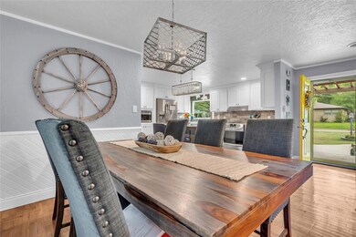 Dining space featuring a textured ceiling, a wainscoted wall, and light wood-style floors