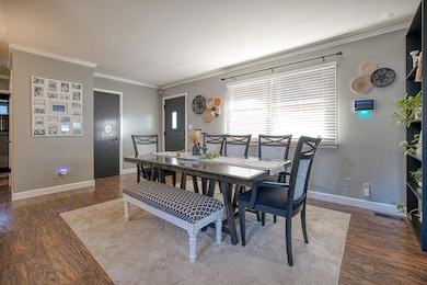 Dining space with wood finished floors and crown molding