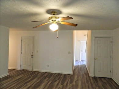Empty room with dark wood-style floors, baseboards